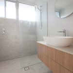 Bathroom with stone tiles and wooden cupboards