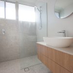 Bathroom with stone tiles and wooden cupboards