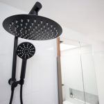 Black shower head in white tiled bathroom